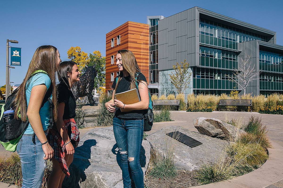 three students standing outside of Jabs Hall in the summer