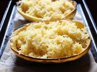 Two halves of a spaghetti squash on a backing sheet.