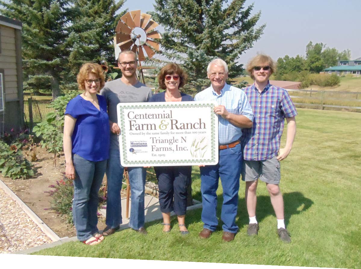 The Nelson family stands with a sign that reads "Centennial Farm & Ranch, Owned by the same family for more than 100 years, Triangle N Farms, Inc. Est 1909"