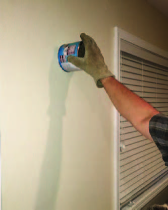 The gloved hand with the can now has the can pinned against the wall, covering the bat.
