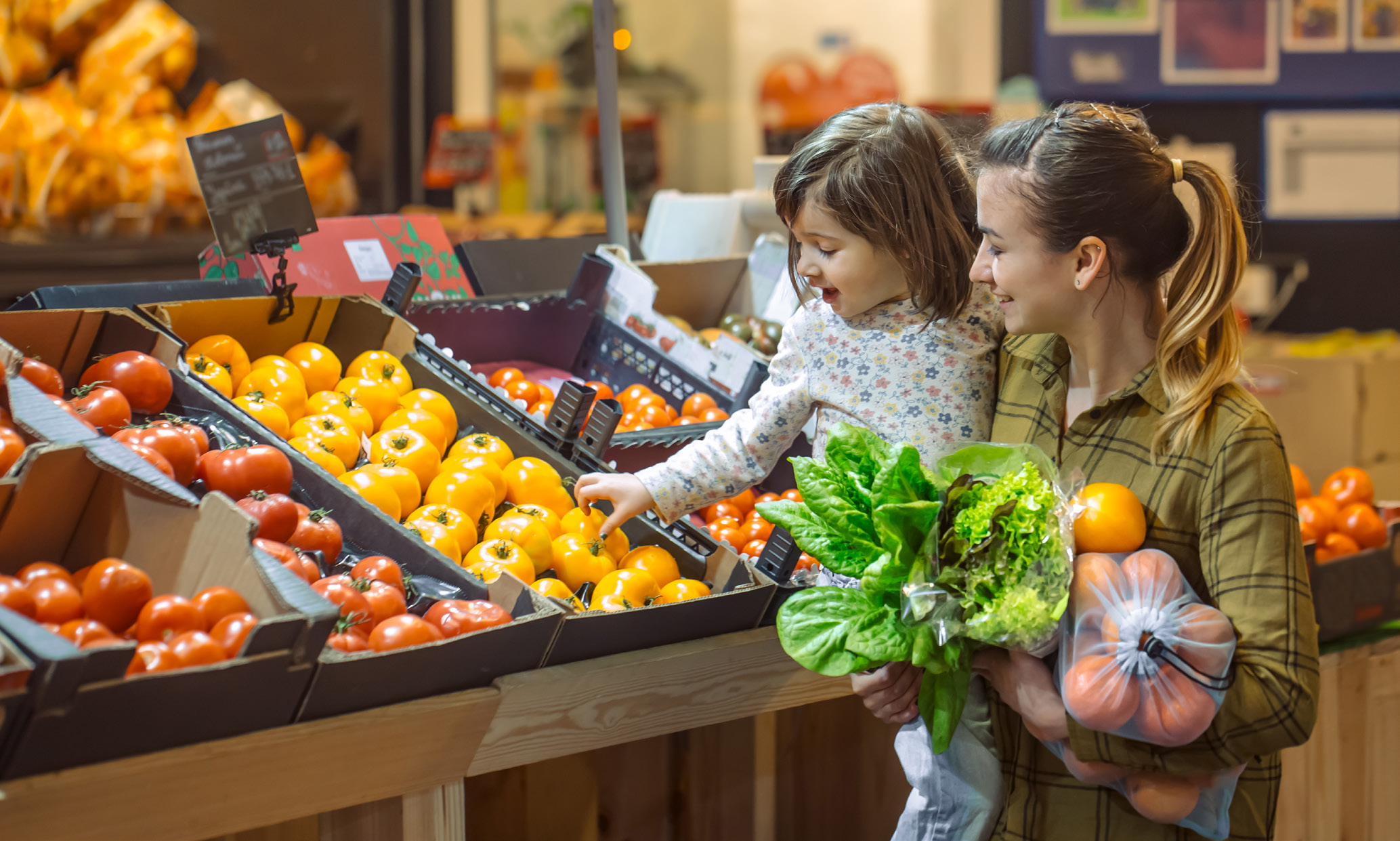 A woman and child shopping for vegetables at a grocery store