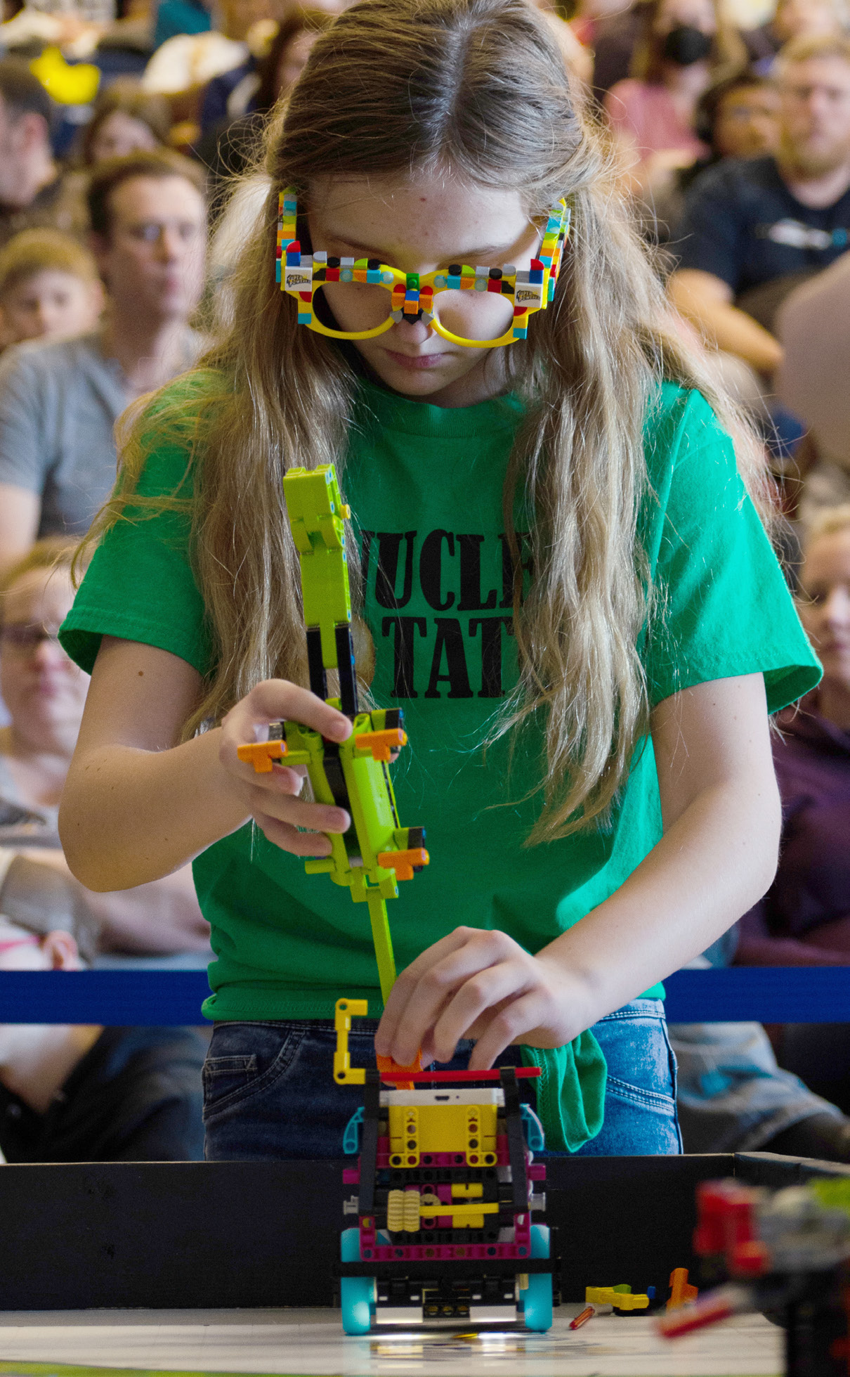 a girl wearing green building her lego robot