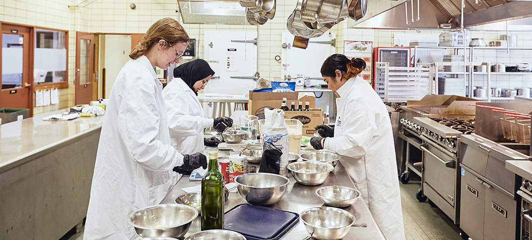 students wearing white lab coats working in Hannon Kitchen