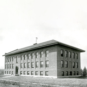 Traphagen Hall is a long rectangular building with three floors. There is an arched doorway that leads into the building.