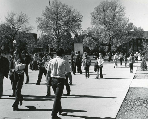 Students walk to class in the 1970s on MSU's Centennial Mall wearing dark colored jeans and bell bottoms.