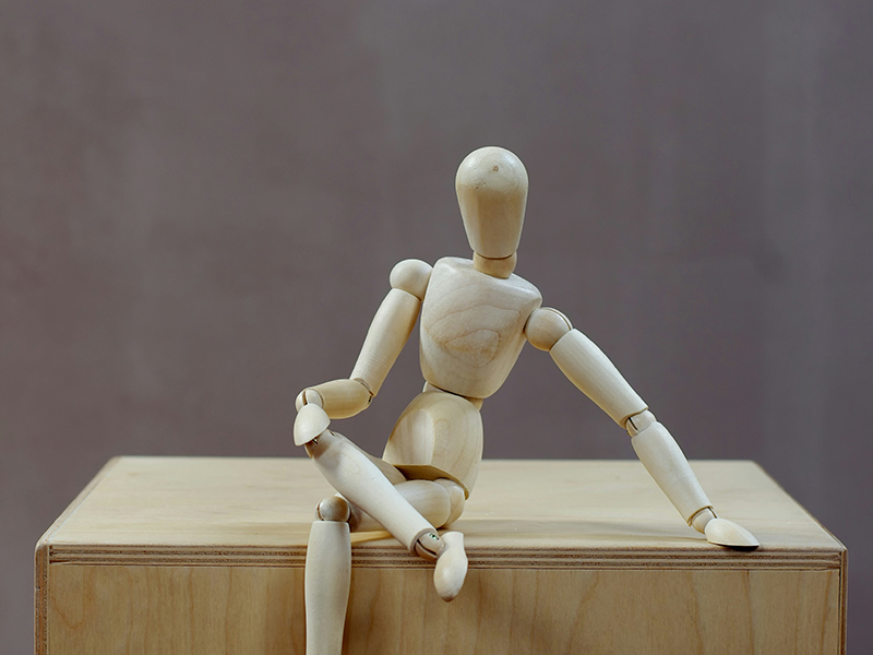 A wooden human model in a sitting pose