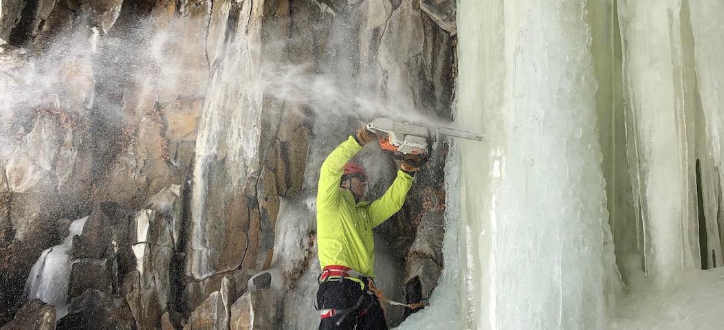 man using chainsaw on ice