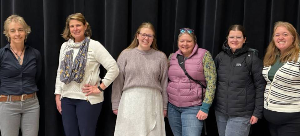 Six staff members smiling against a black background