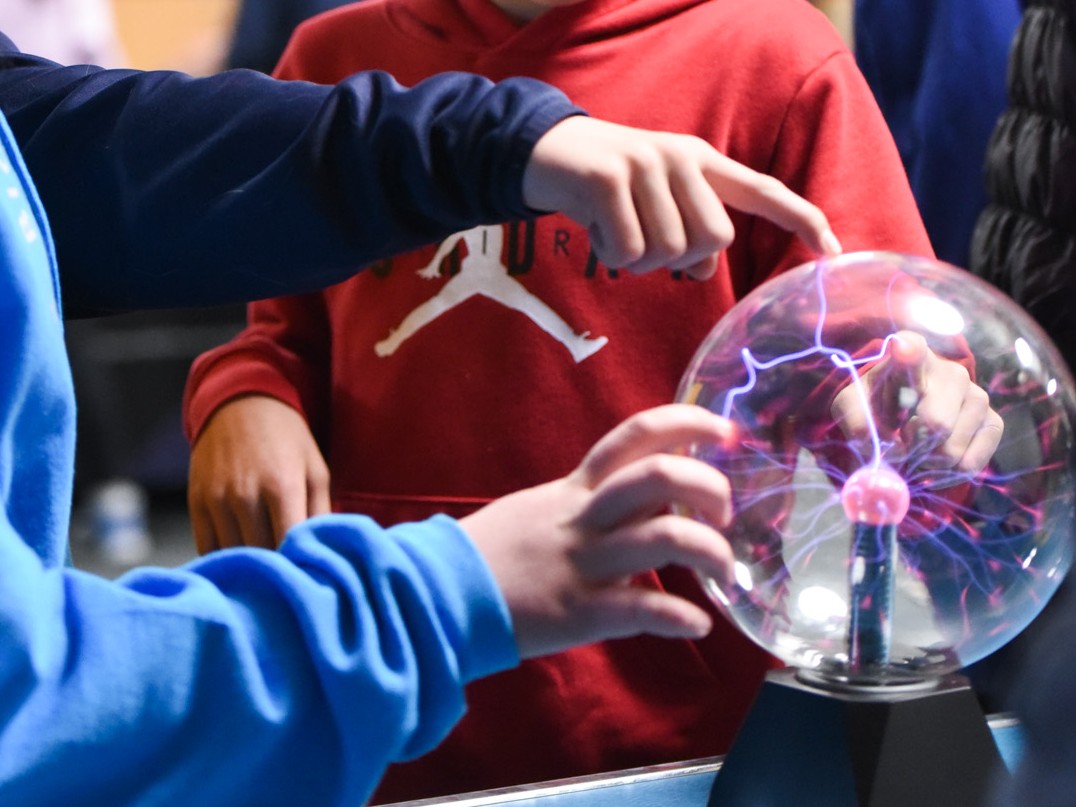 Elementary students touch a plasma ball
